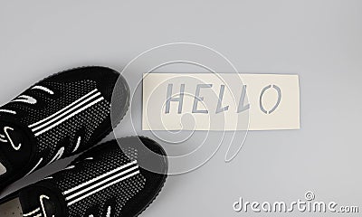 The word hello on a white background next to casual summer shoes.World Greetings Day. The day of winning friends. Stock Photo