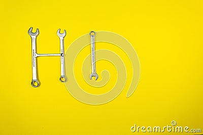 Word `Hi` laid out with wrenches on a yellow background Stock Photo