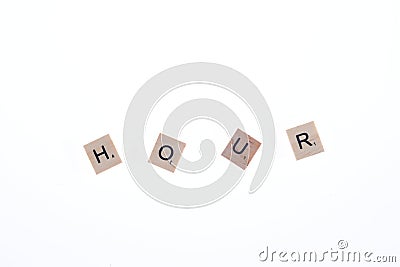 Word hour arranged from wooden blocks on white background. Game Editorial Stock Photo