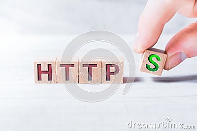 The Word HTTPS Formed By Wooden Blocks And Arranged By Male Fingers On A White Table Stock Photo