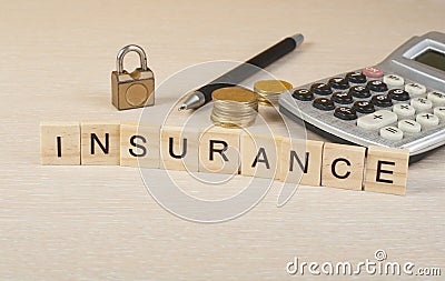 Word INSURANCE on wooden cubes. Calculator, pen,coins and padlock on the table. Insurance and saving concept. Stock Photo