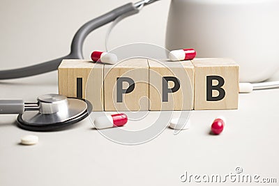 word ippb is made of wooden cubes on a yellow background with pills. medical concept of treatment, prevention and side effects Stock Photo