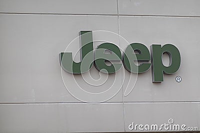 The word Jeep in green letters is seen on the white exterior wall of a car dealership building Editorial Stock Photo