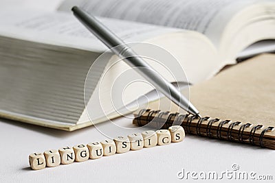 The word linguistics next to an open book, notepad and pen. The concept of studying the humanities in college: literature, Stock Photo