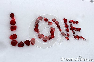 Word Love made of pomegranate seeds on white snow. Stock Photo