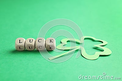 Word LUCK made with wooden cubes and paper clover leaf on background Stock Photo