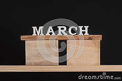 Word March written on wooden blocks on wooden shelf. Black background. Spring calendar Stock Photo