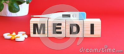 The word MEDI is made of wooden cubes on a red background. Medical concept Stock Photo