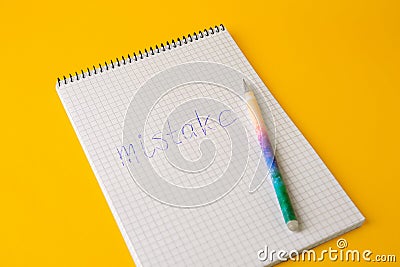 Word Mistake written with erasable pen in notepad on yellow background, closeup Stock Photo