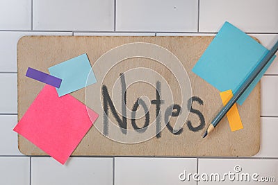 The word Notes painted on wooden sign with posted multiple colored note pads Stock Photo