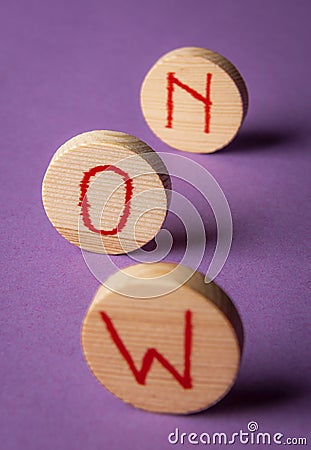 Word now on wooden pieces. Seize the moment. Purple background Stock Photo