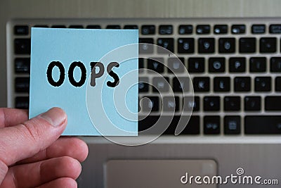 Word OOPS on sticky note hold in hand on keyboard background Stock Photo