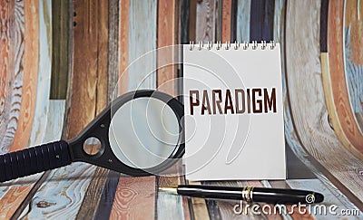 The word paradigm is written on a white notebook, near a pen and a magnifying glass Stock Photo