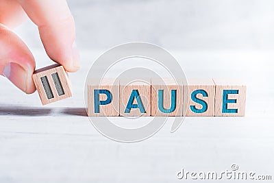 The Word Pause Formed By Wooden Blocks And Arranged By Male Fingers On A White Table Stock Photo