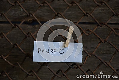 Word pause is written in English on a sheet of white paper hanging on the fence on the filler Stock Photo