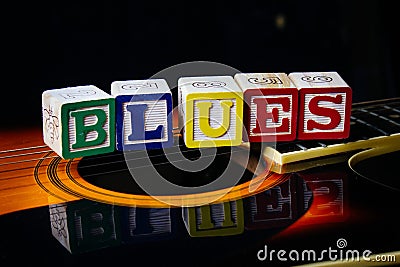 Word or phrase Blues made with letter cubes, standing on guitar. Stock Photo