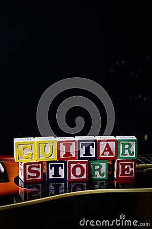 Word or phrase Guitar Store made with letter cubes, standing on guitar. Stock Photo