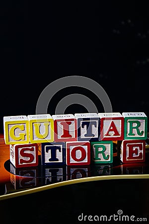 Word or phrase Guitar Store made with letter cubes, standing on guitar. Stock Photo