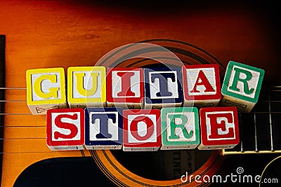 Word or phrase Guitar Store made with letter cubes, standing on guitar. Stock Photo