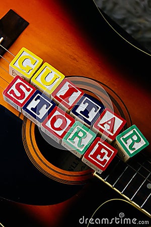 Word or phrase Guitar Store made with letter cubes, standing on guitar. Stock Photo