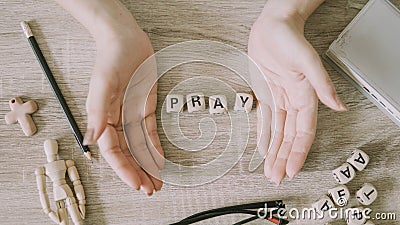 Word PRAY made from cubes or blocks with woman hands on wood background Stock Photo