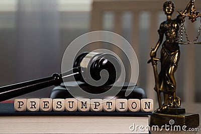 Word PRESUMPTION composed of wooden dices. Wooden gavel and statue of Themis in the background Stock Photo