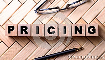 The word PRICING is written on wooden cubes on a wooden background next to a pen and glasses Stock Photo