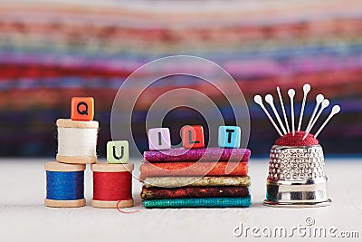 The word QUILT is made up of imitation jewelry cubes surrounded sewing accessories Stock Photo