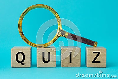 Word Quiz written on wooden blocks and a magnifying glass on a blue background, concept of questions and answers in game shows Stock Photo