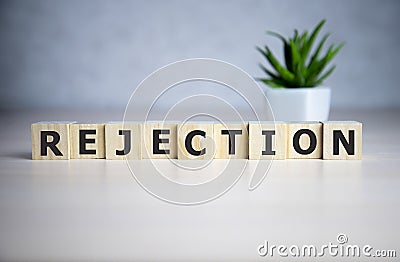 The word REJECTION, spelt with wooden letter tiles over a blue background Stock Photo