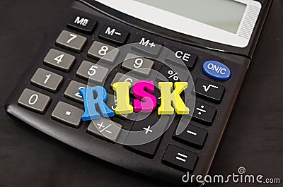 The word `risk` from the letters lies on the calculator. Close-up. The concept of business risk, economic crisis. Stock Photo