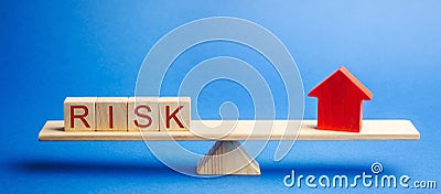 The word risk and a miniature house on the scales. The concept of mortgage, loans and real estate. Taxes and debts. Property Stock Photo