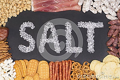 Word salt written with sea salt surrounded by food containing a lot of salt Stock Photo