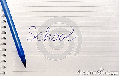 The word school written in blue pen on a notebook with lines and a blue pen. Stock Photo