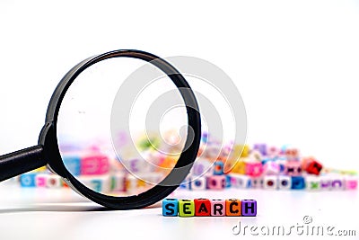 Word `SEARCH` on the magnifying glass with alphabet letter beads background Stock Photo