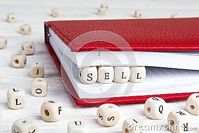 Word Sell written in wooden blocks in red notebook on white wood Stock Photo