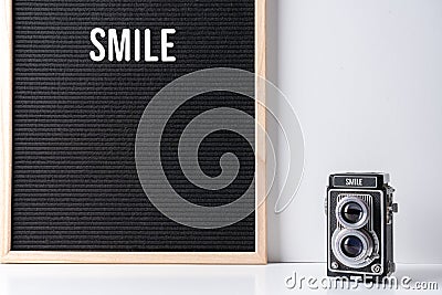 The word smile on camera and on black letter board. Text, quote and creative concept. Stock Photo