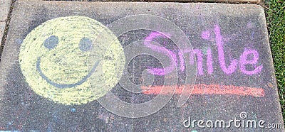 The word Smile" and smiley face emoji sidewalk chalk Stock Photo