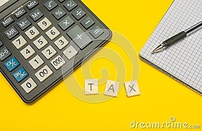 Word tax made with wood letters on yellow background and modern calculator with pen and notebook. Copy space. Economy, money Stock Photo