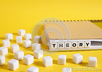 The word Theory written on cubes in a notebook on yellow background Stock Photo