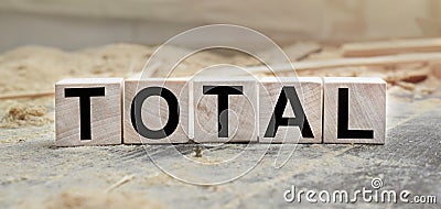 The word TOTAL is written on wooden cubes. Wooden cubes lie on the table with sawdust and wooden blocks. Designed to promote your Stock Photo