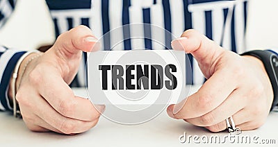 Word Trends on a white card in woman hands. Business concept Stock Photo