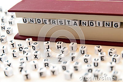 Word understanding written with letters between a book pages white background with letters spread around education reading concept Stock Photo