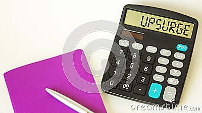 The word Upsurge , on a calculator, next to a notepad with a pen Stock Photo