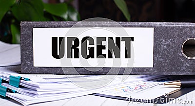 The word URGENT is written on a gray file folder next to documents. Business concept Stock Photo