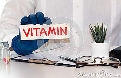 word Vitamin written on a card in doctors hands Stock Photo
