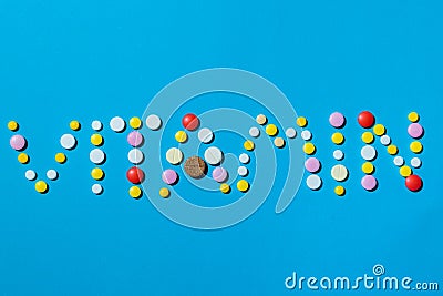 Word vitamin written with colorful pills on a blue background, the concept of supplement needed for a healthy life. Stock Photo