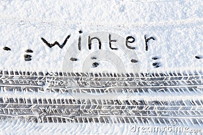 Word winter and tire tracks in snow on road Stock Photo