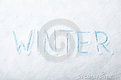 Word WINTER written in snow on color background Stock Photo