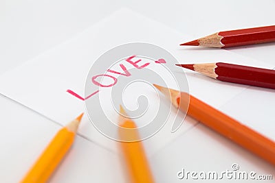 Wording Love in Red color with little heart on the small paper , encircle with color pencils in warm tone Stock Photo